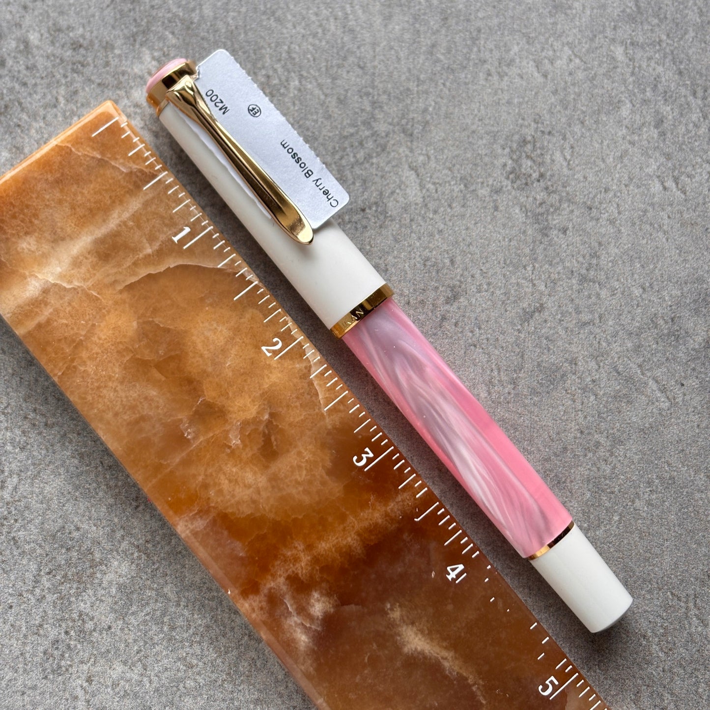 Pen with pink and gold accents on a marble surface with a ruler