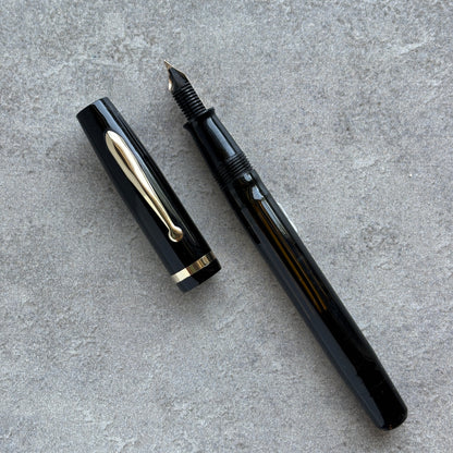 Black fountain pen and cap on a gray concrete surface