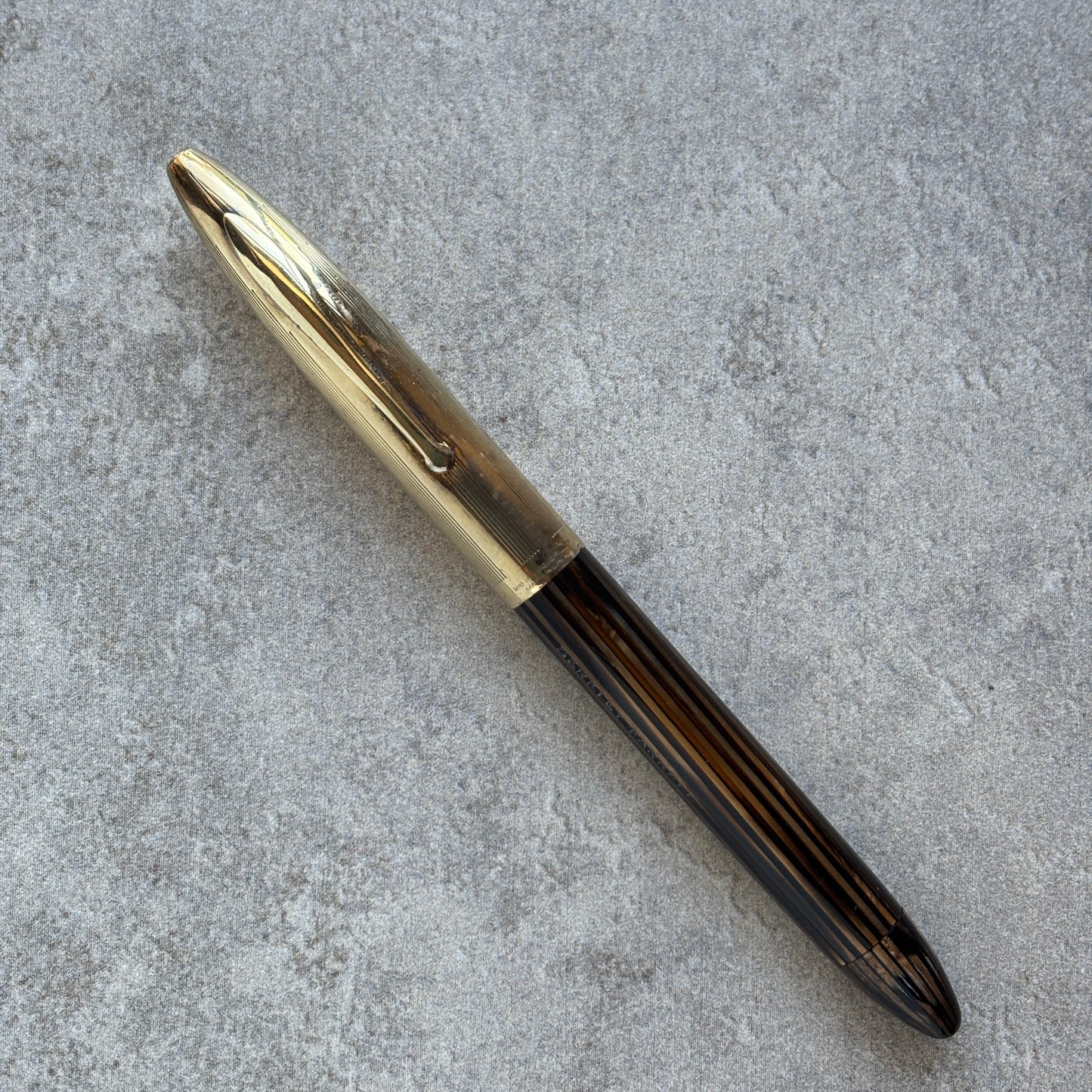 Pen with gold cap and black body on a gray concrete surface