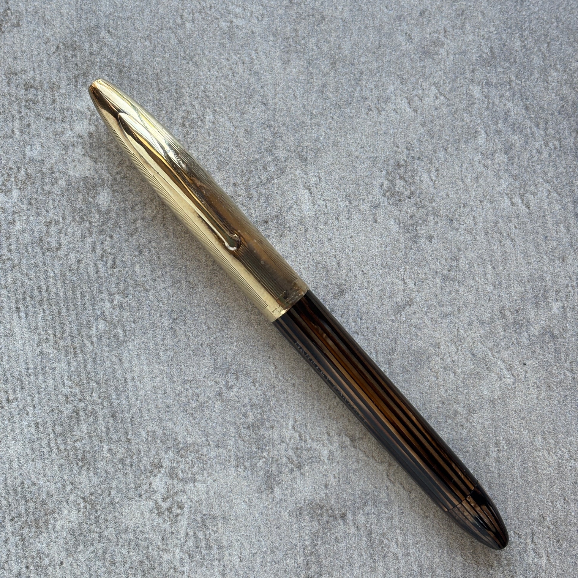 Pen with gold cap and black body on a gray concrete surface