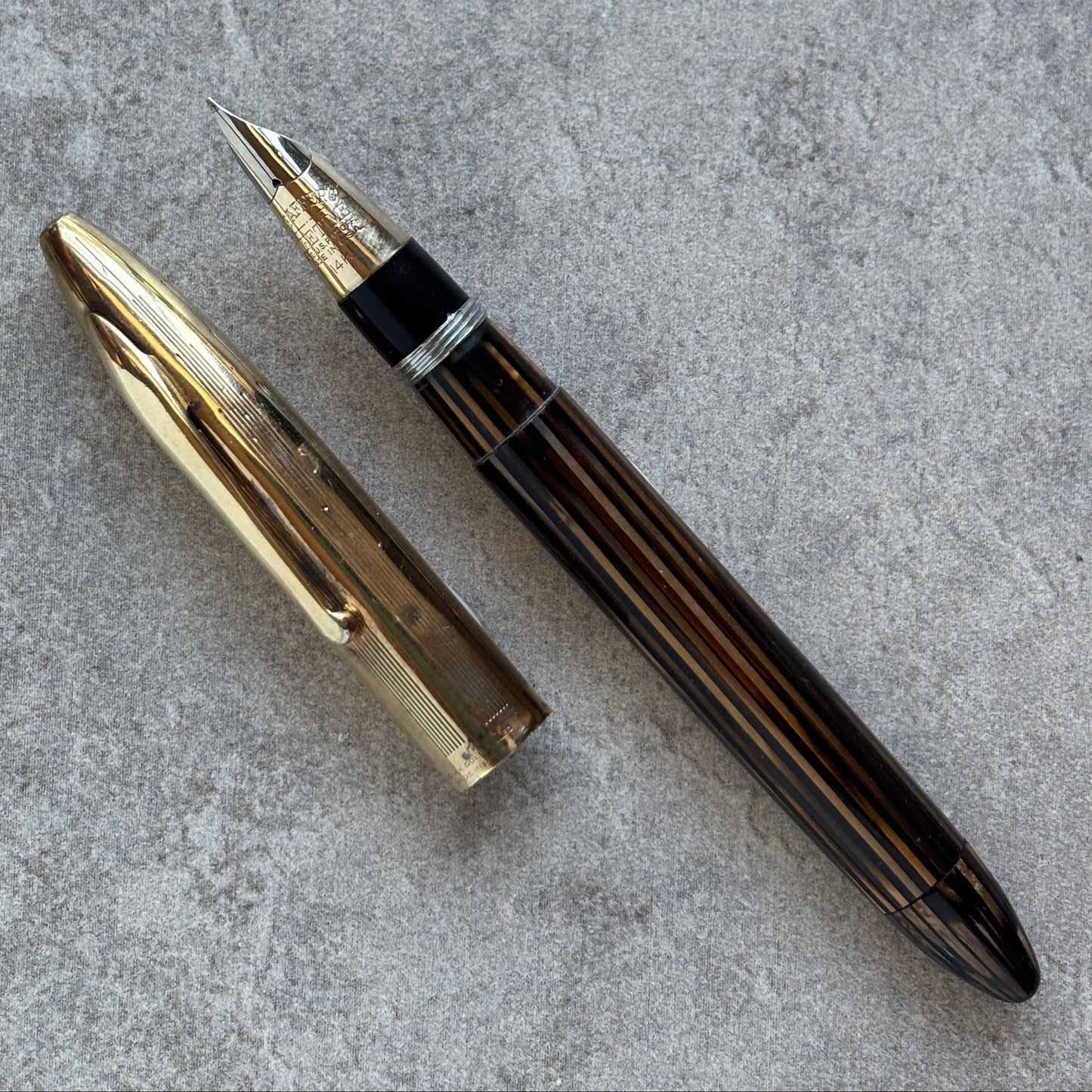 Fountain pen with gold cap on a gray textured surface