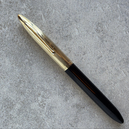Pen with gold cap and black body on a gray concrete surface