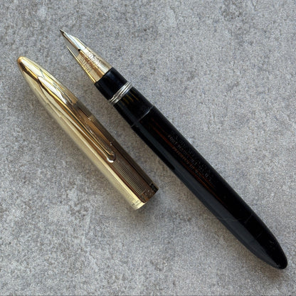 Gold and black pen on a gray textured surface