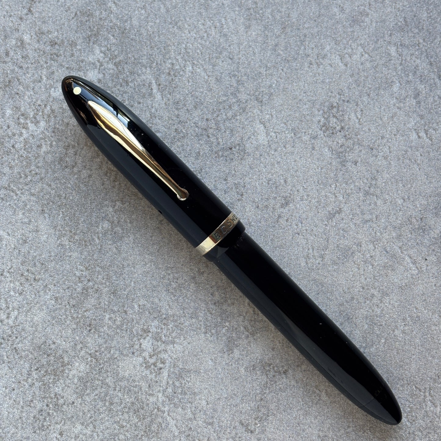 Black pen with gold accents on a gray concrete surface