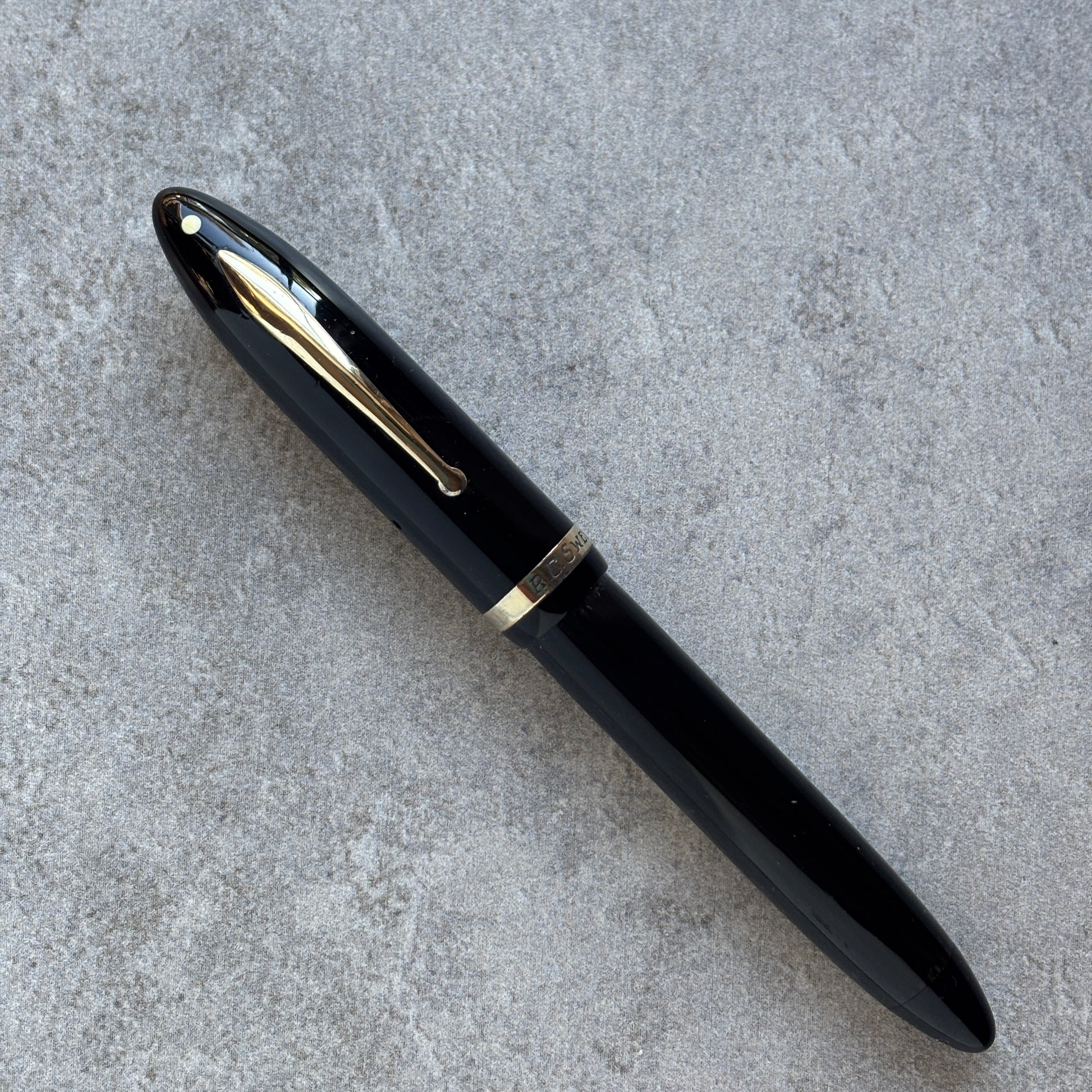 Black pen with gold accents on a gray concrete surface