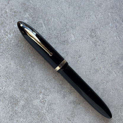 Black pen with gold accents on a gray concrete surface