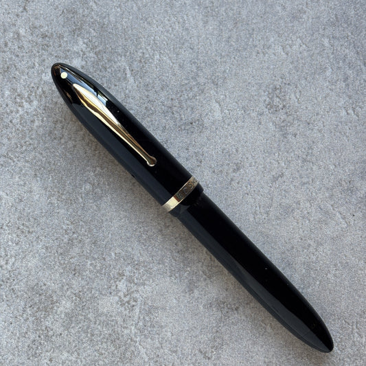 Black pen with gold accents on a gray concrete surface