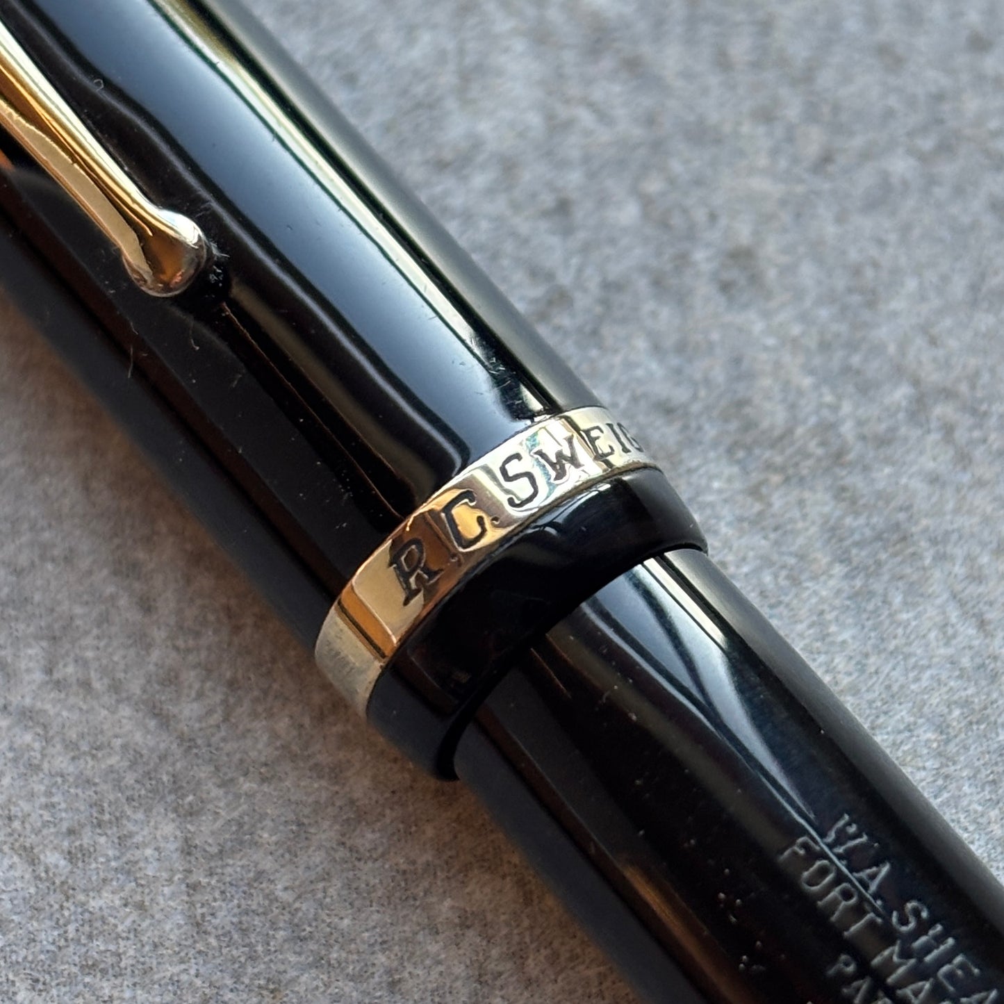 Close-up of a black pen with gold accents on a textured gray background