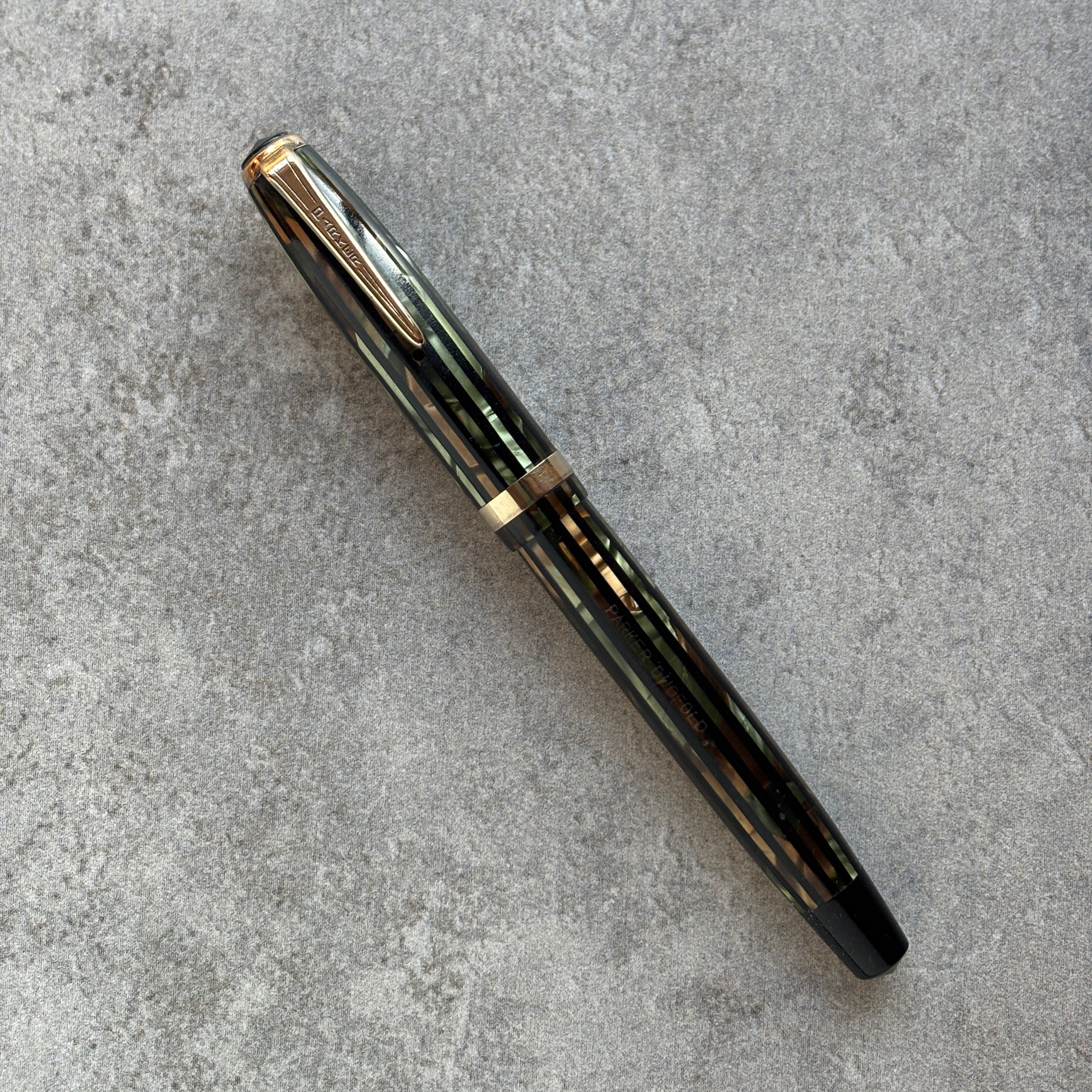 Green and Gold Striped fountain pen with gold accents on a gray surface