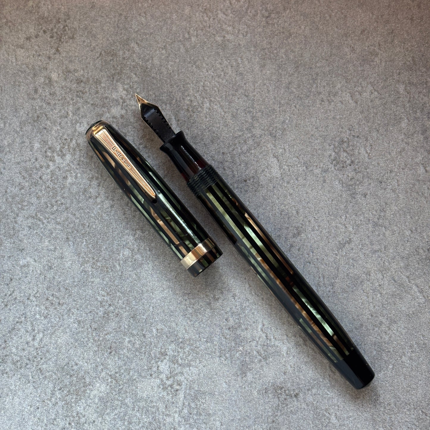 Fountain pen and its cap on a gray surface