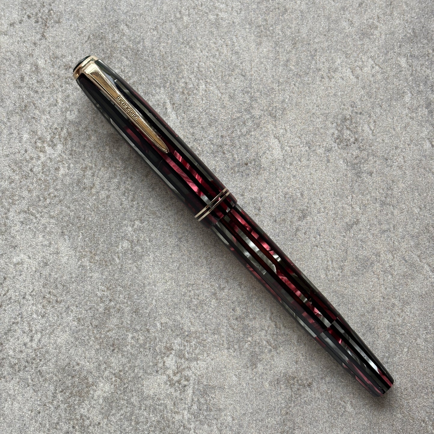 Fountain pen with black and red with gold accents on a gray textured surface