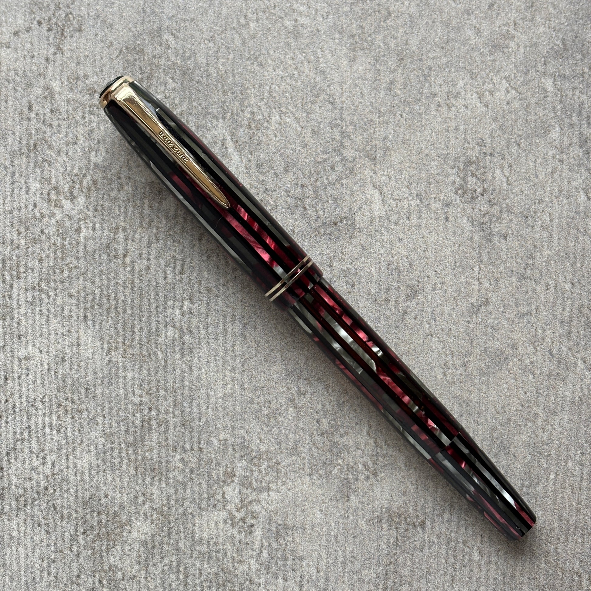 Fountain pen with black and red with gold accents on a gray textured surface