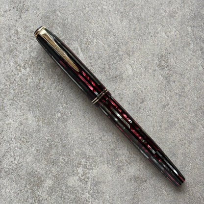 Fountain pen with black and red with gold accents on a gray textured surface