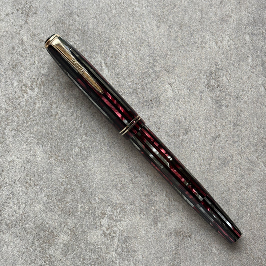 Fountain pen with black and red with gold accents on a gray textured surface