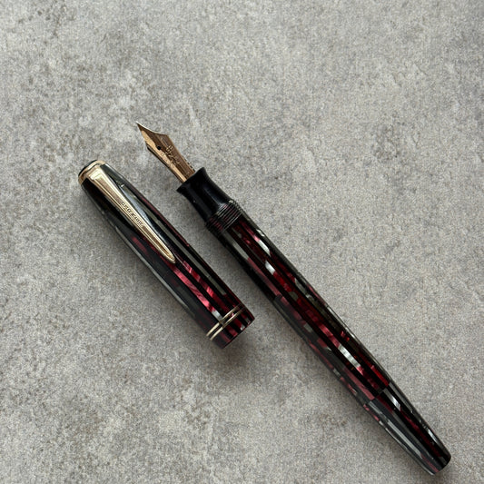 Fountain pen with red and black stripes on a gray concrete surface