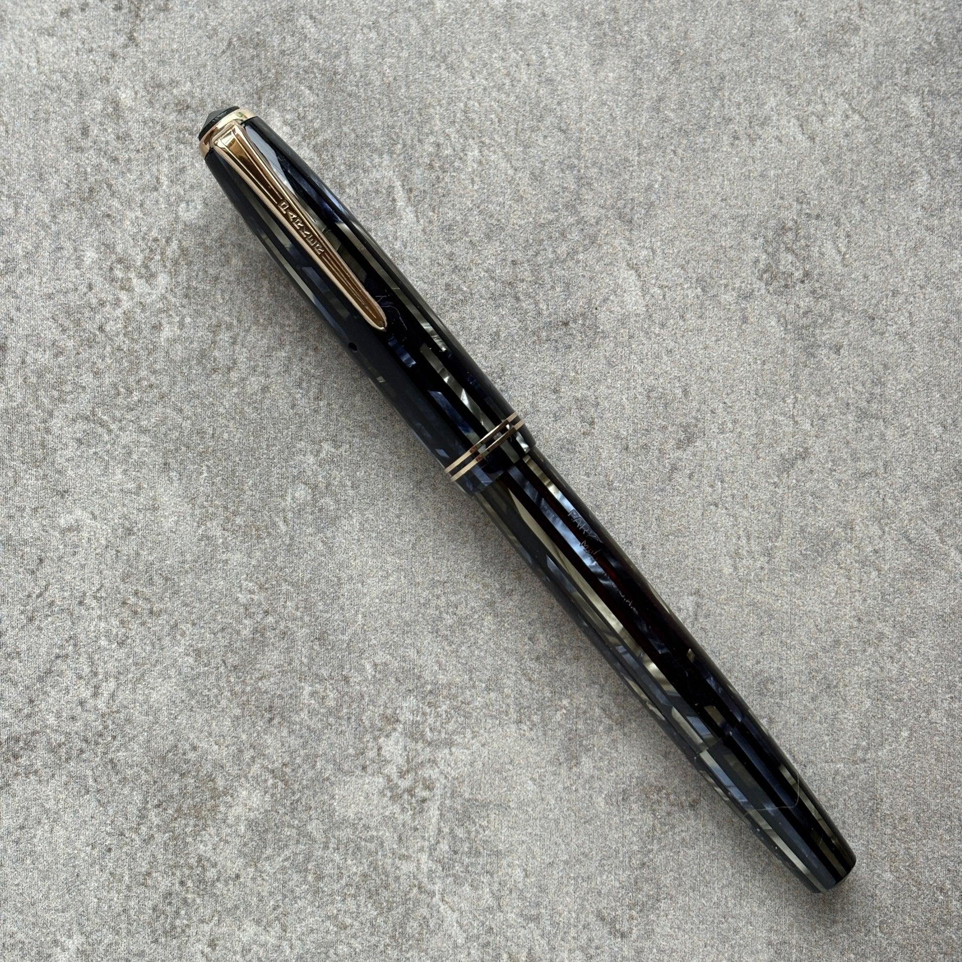 Black and blue fountain pen with gold accents on a gray concrete surface