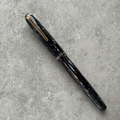 Black and blue fountain pen with gold accents on a gray concrete surface