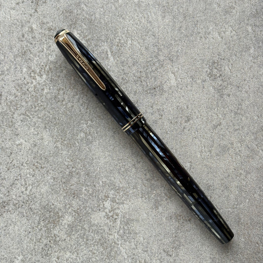 Black and blue fountain pen with gold accents on a gray concrete surface