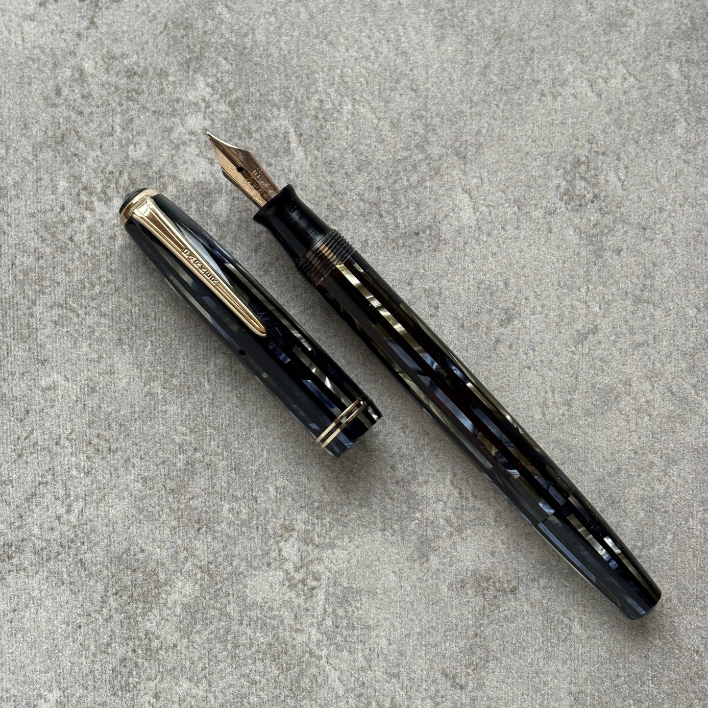 Black and blue  fountain pen with gold accents on a gray concrete surface