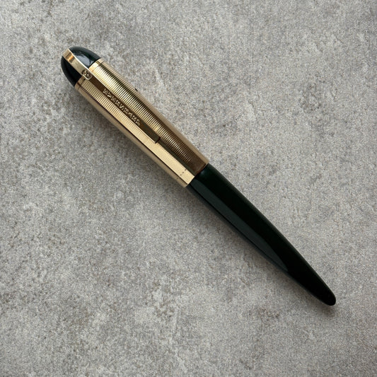 Green Pen with gold and black accents on a gray surface