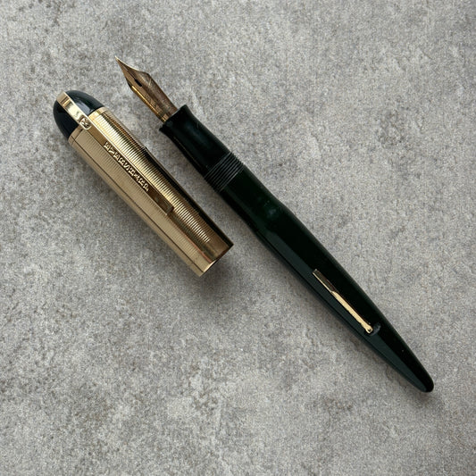 Fountain pen with gold accents on a gray concrete surface