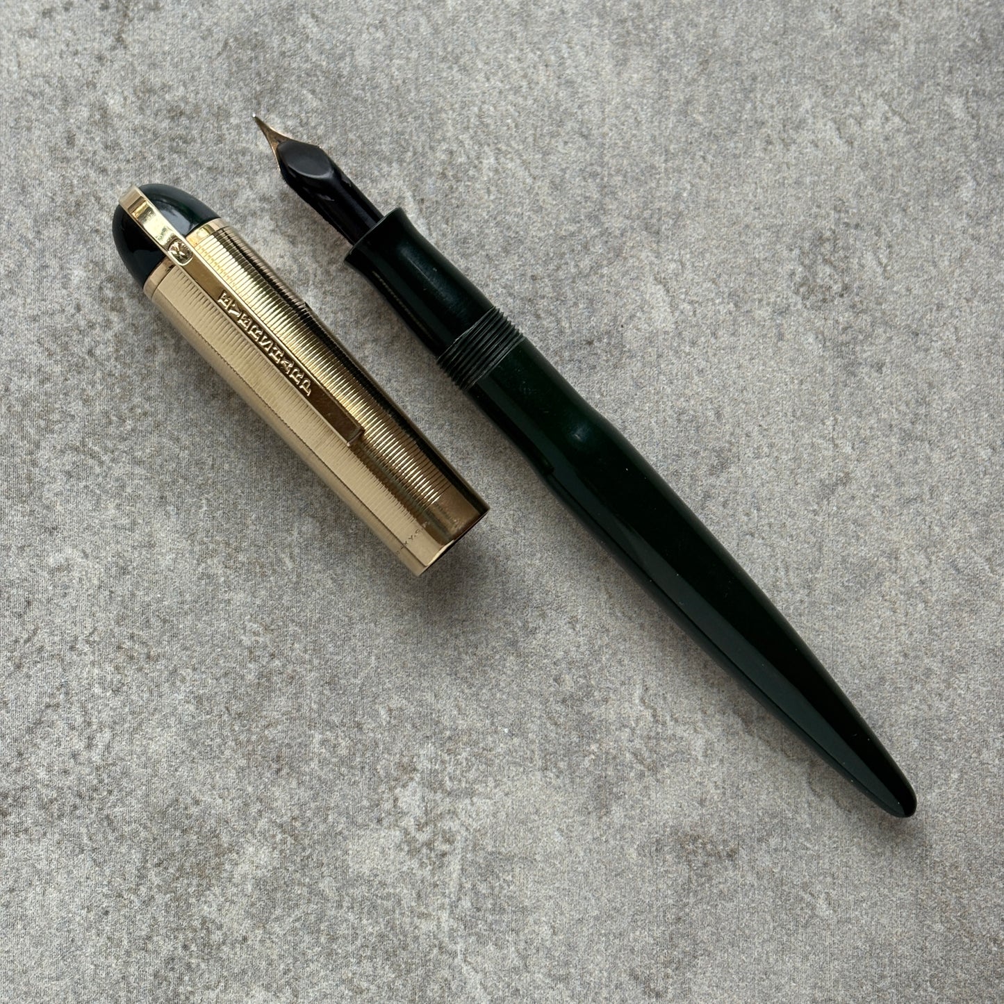 Fountain pen with gold accents on a gray concrete surface