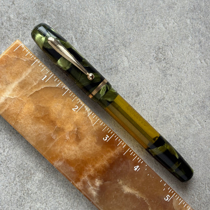 Pen with green and black accents on a textured surface next to a ruler