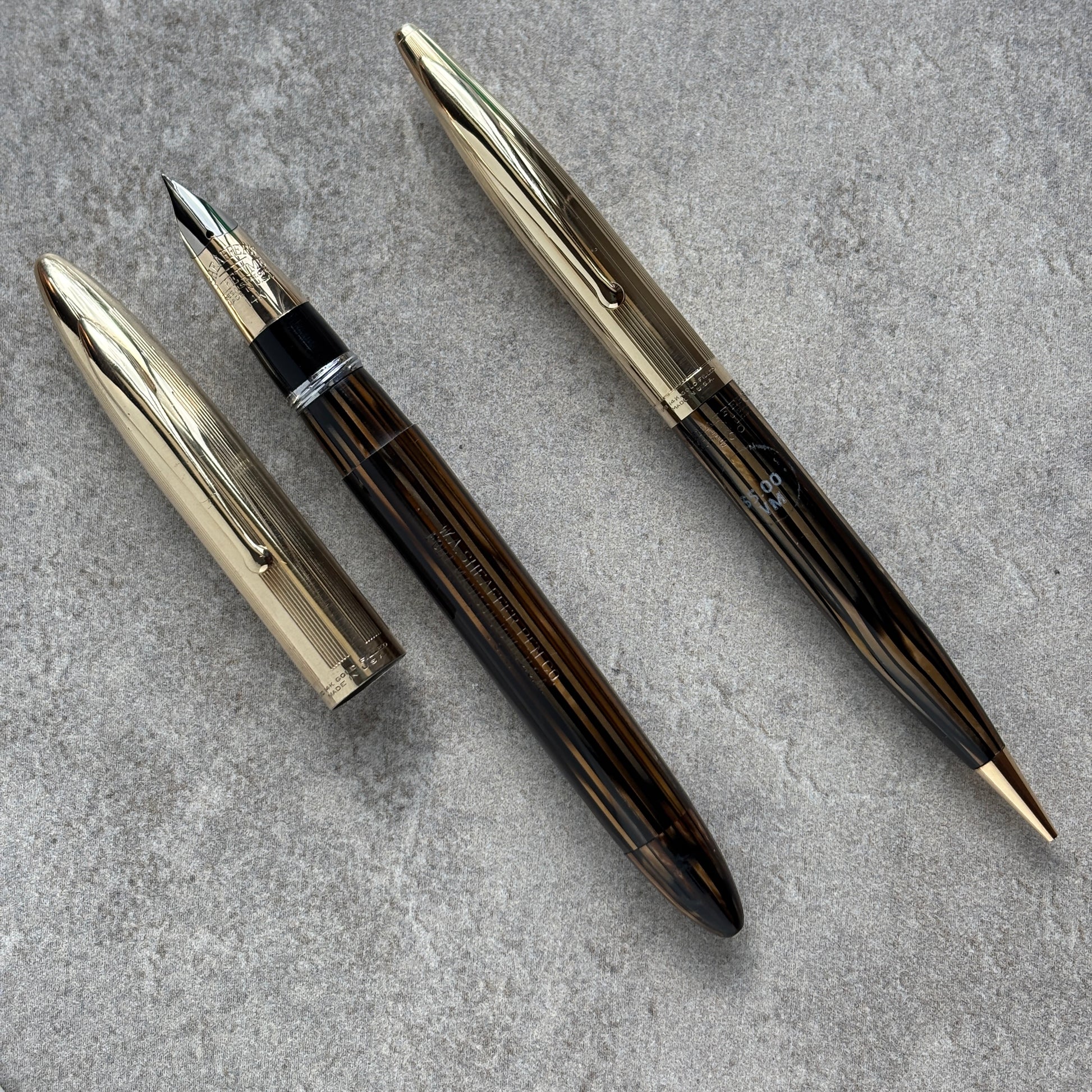 fountain pen and pencil set on a gray textured surface