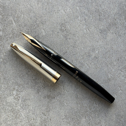 Black and gold fountain pen on a gray concrete surface