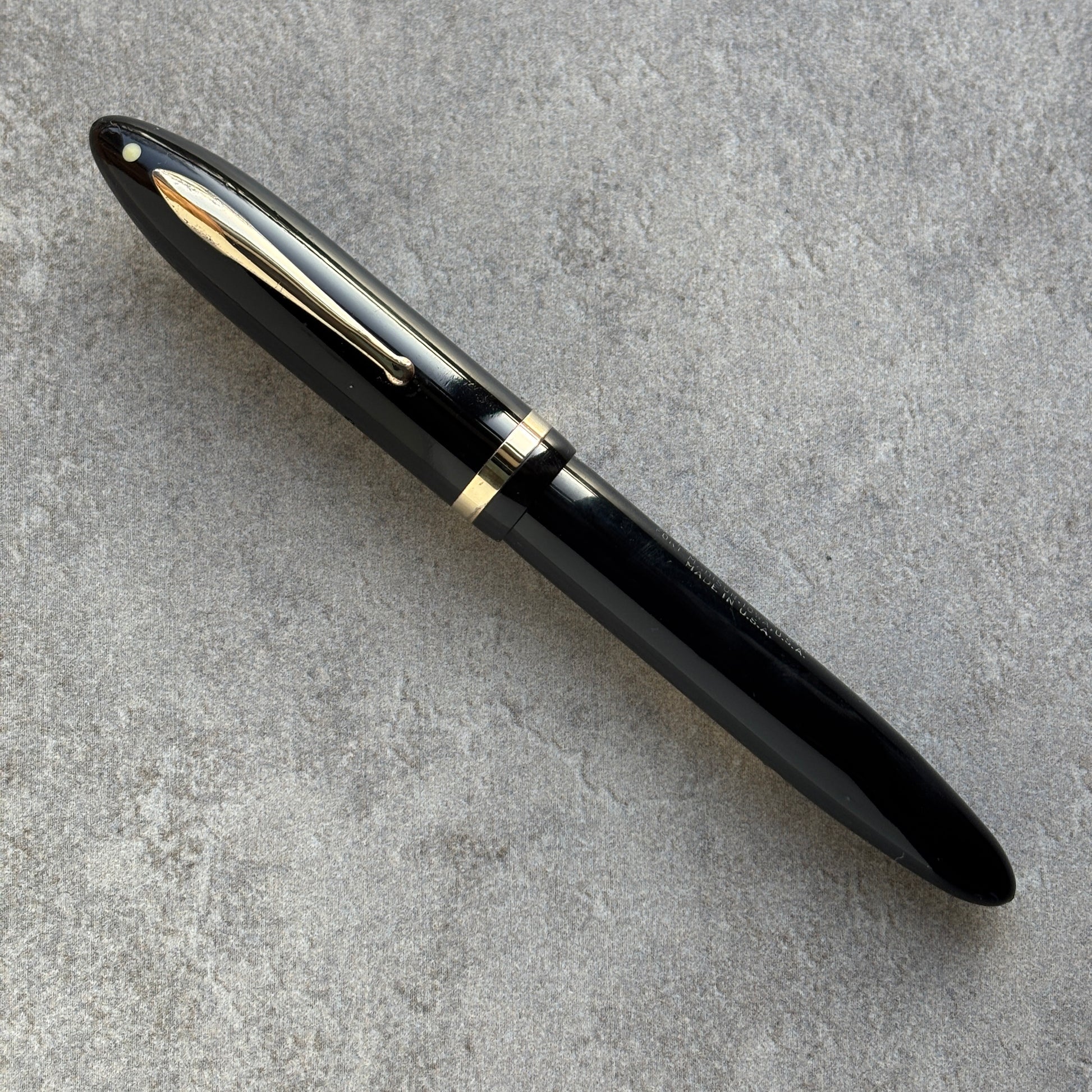Black fountain pen with gold accents on a gray concrete surface