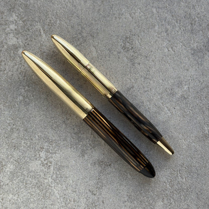 Gold and black pen on a gray concrete surface