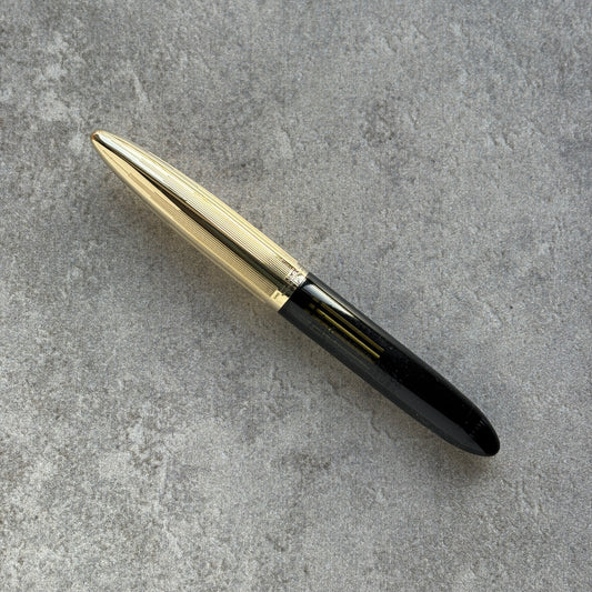 Gold and black pen on a gray concrete surface