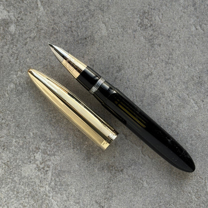 Gold and black pen on a gray concrete surface