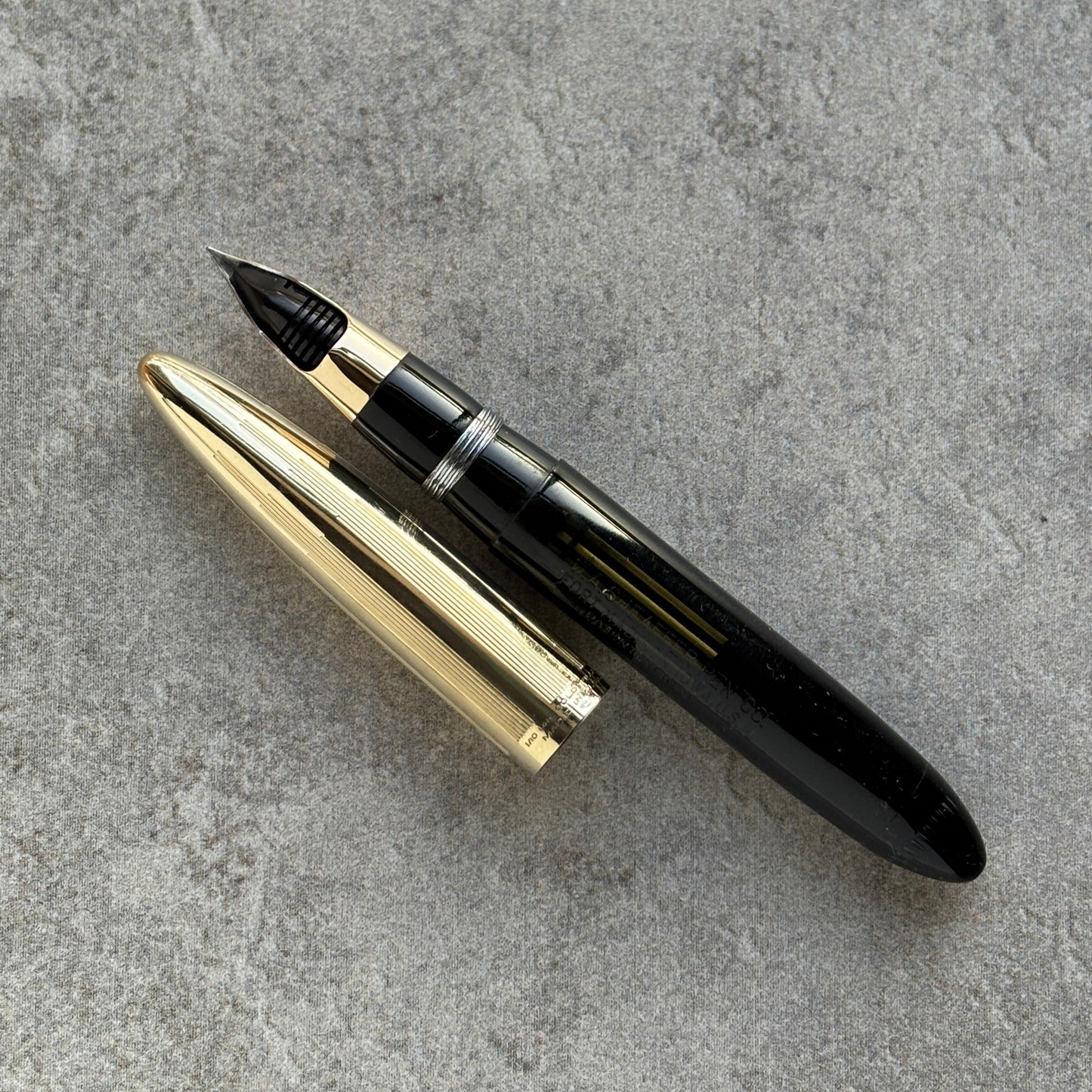 Fountain pen with gold accents on a gray concrete surface