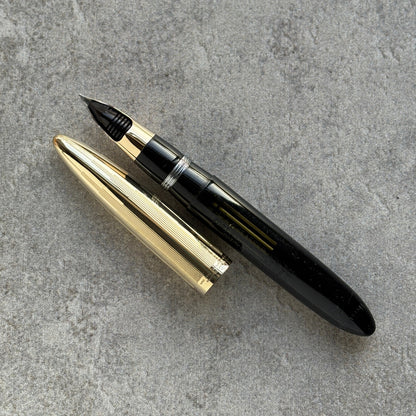 Fountain pen with gold accents on a gray concrete surface