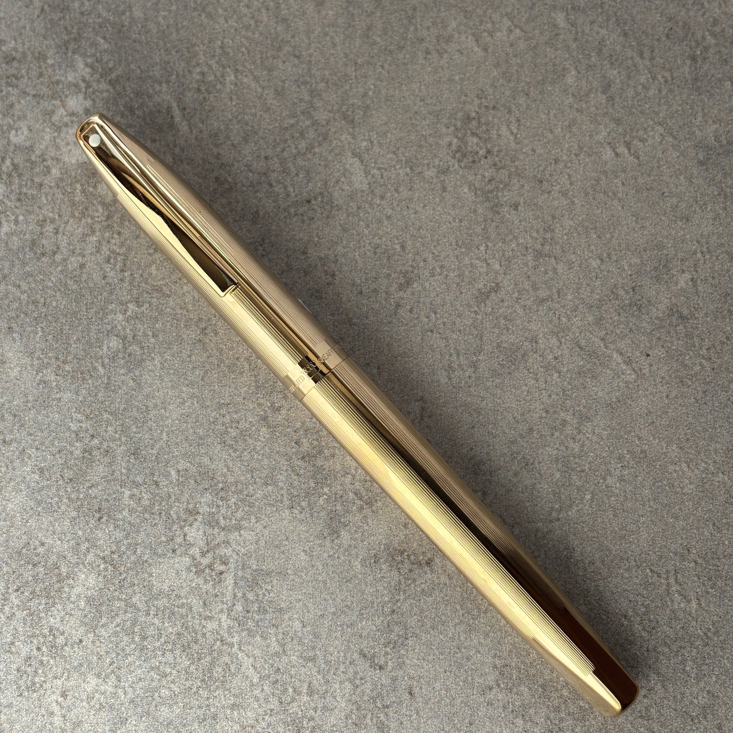 Gold pen on a gray concrete surface