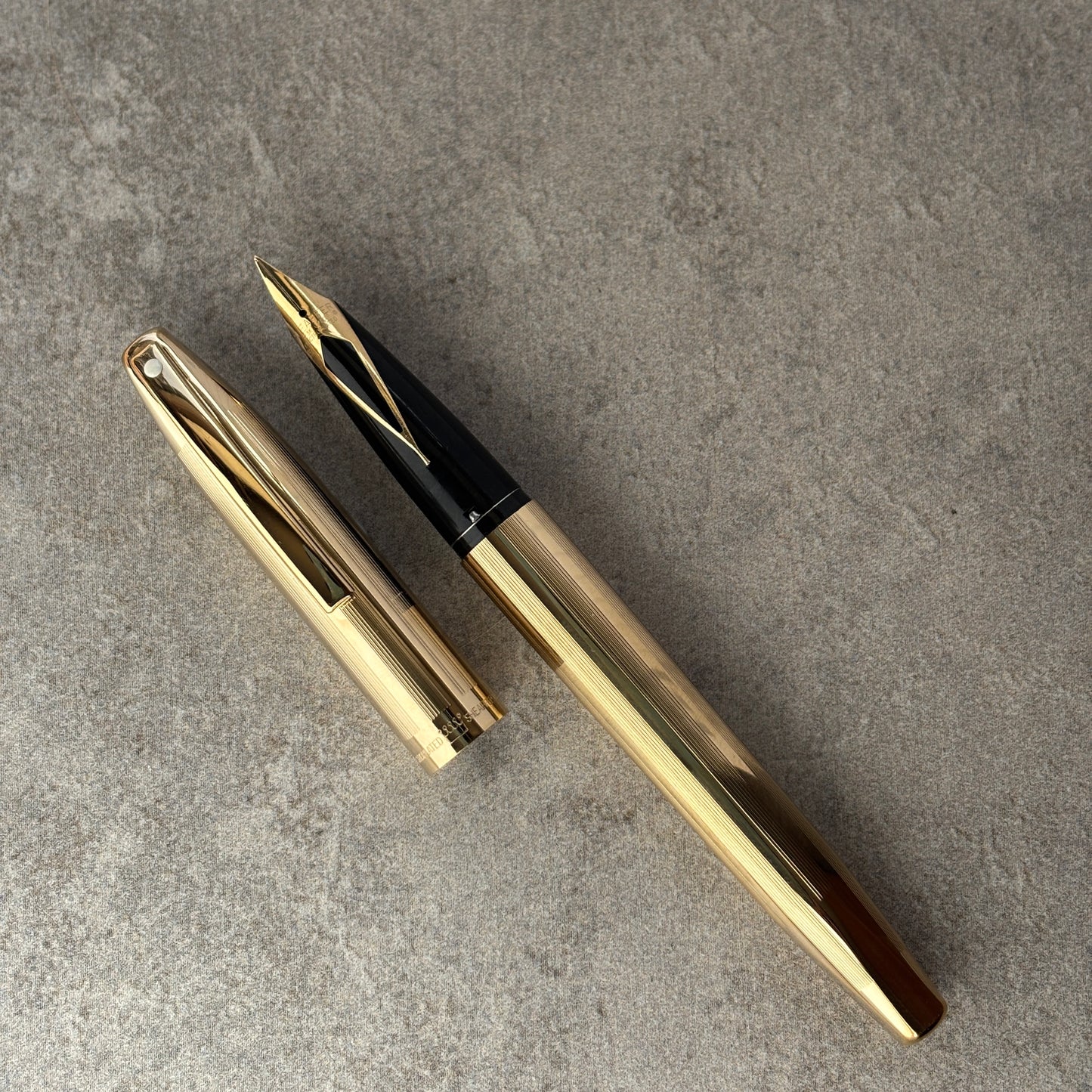 Gold fountain pen on a gray concrete surface
