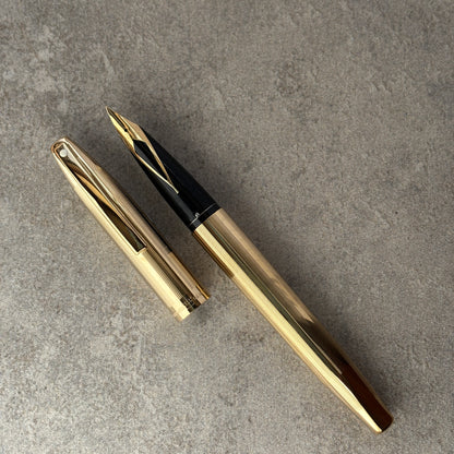 Gold fountain pen on a gray concrete surface