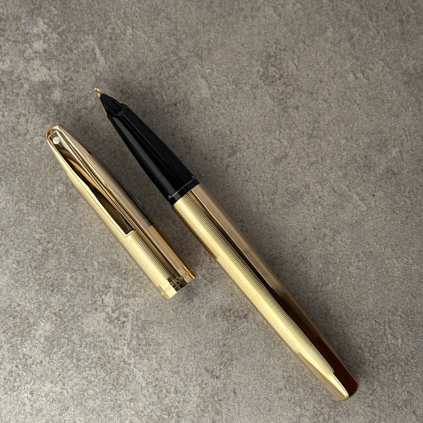 Gold and black fountain pen on a gray surface