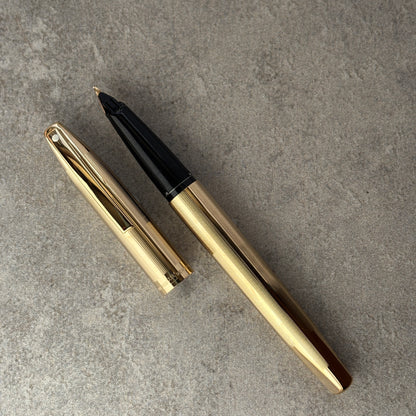 Gold and black fountain pen on a gray surface