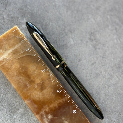 Fountain pen on a marble slab with a ruler for scale against a gray background