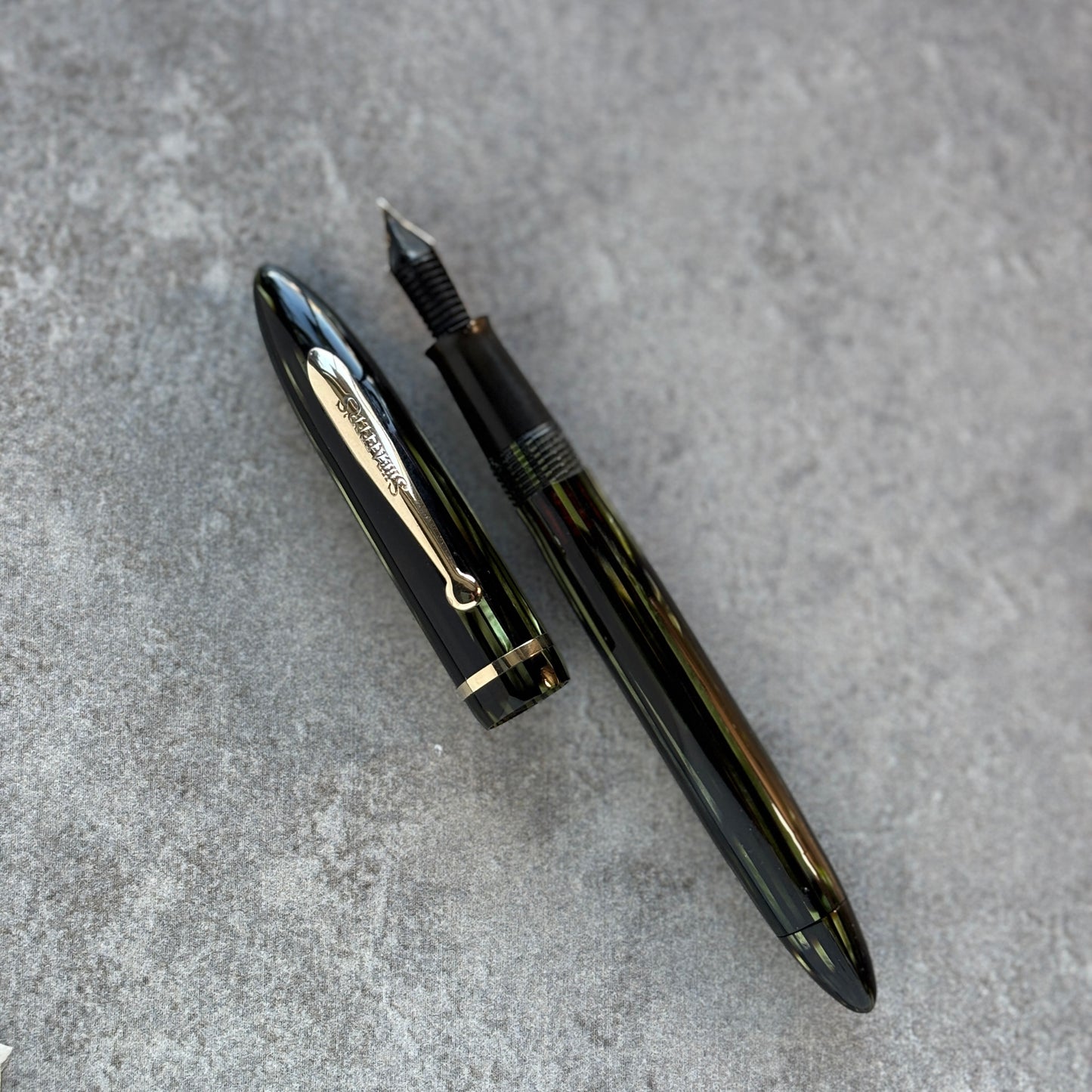 Green fountain pen on a gray textured surface