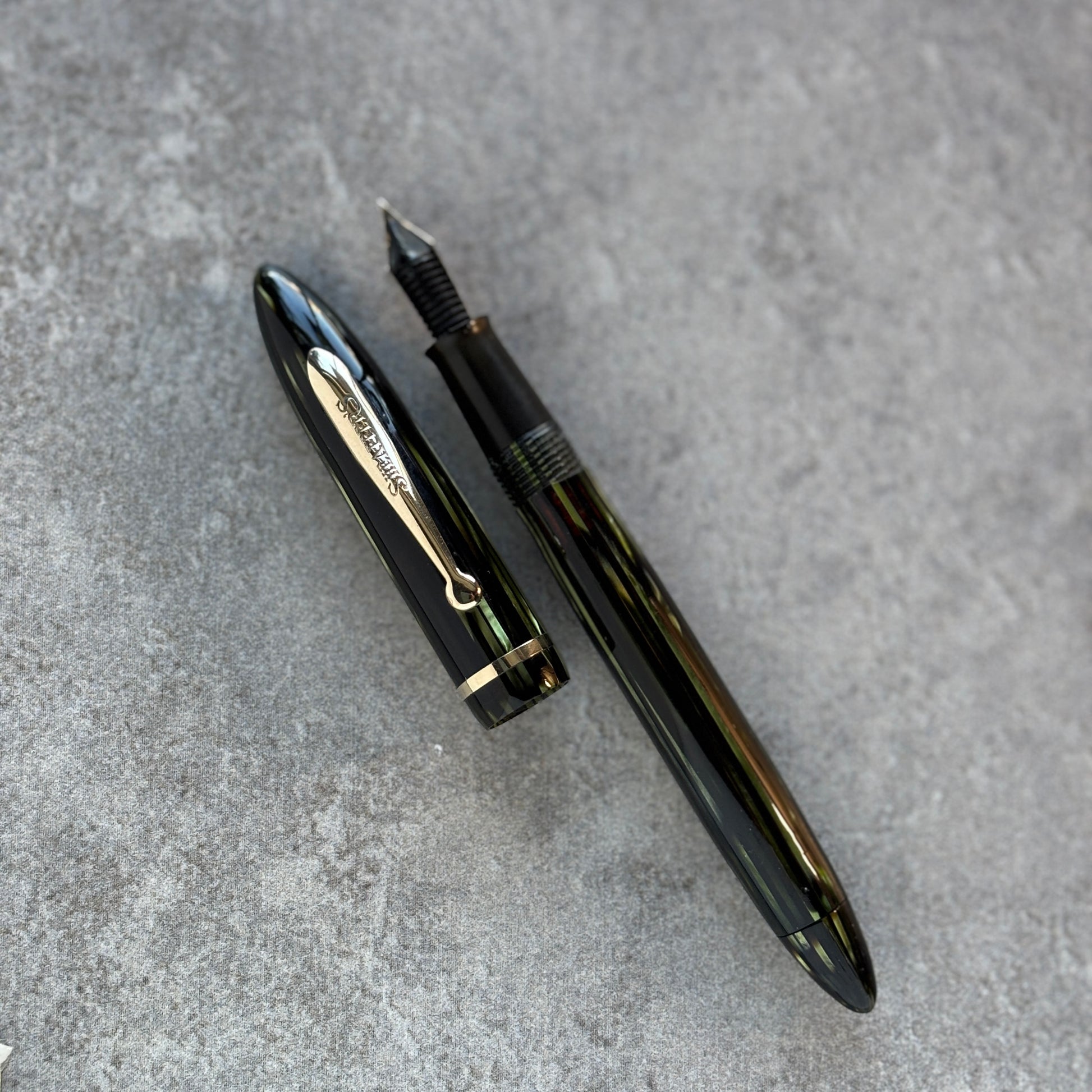 Green fountain pen on a gray textured surface