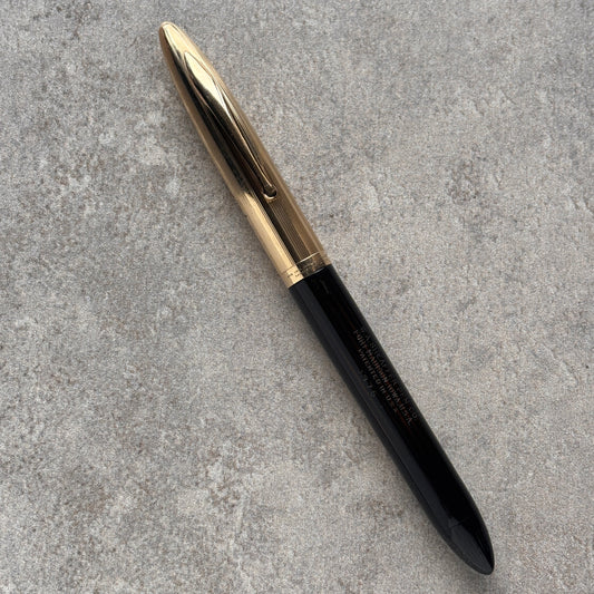 Black pen with gold cap on a gray textured surface