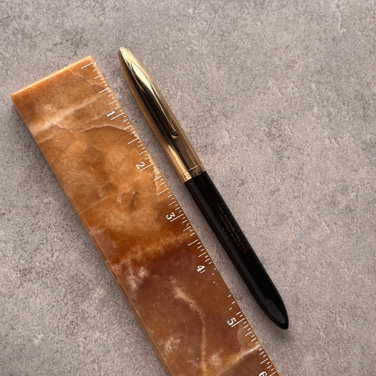 Marble-textured ruler with a pen on a gray surface