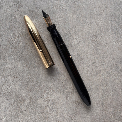 Black fountain pen and gold nib on a gray concrete surface