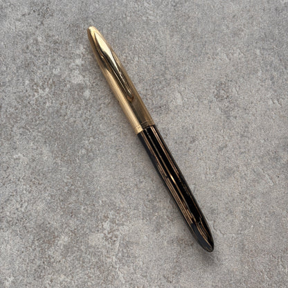Pen with gold cap and black body on a gray textured surface