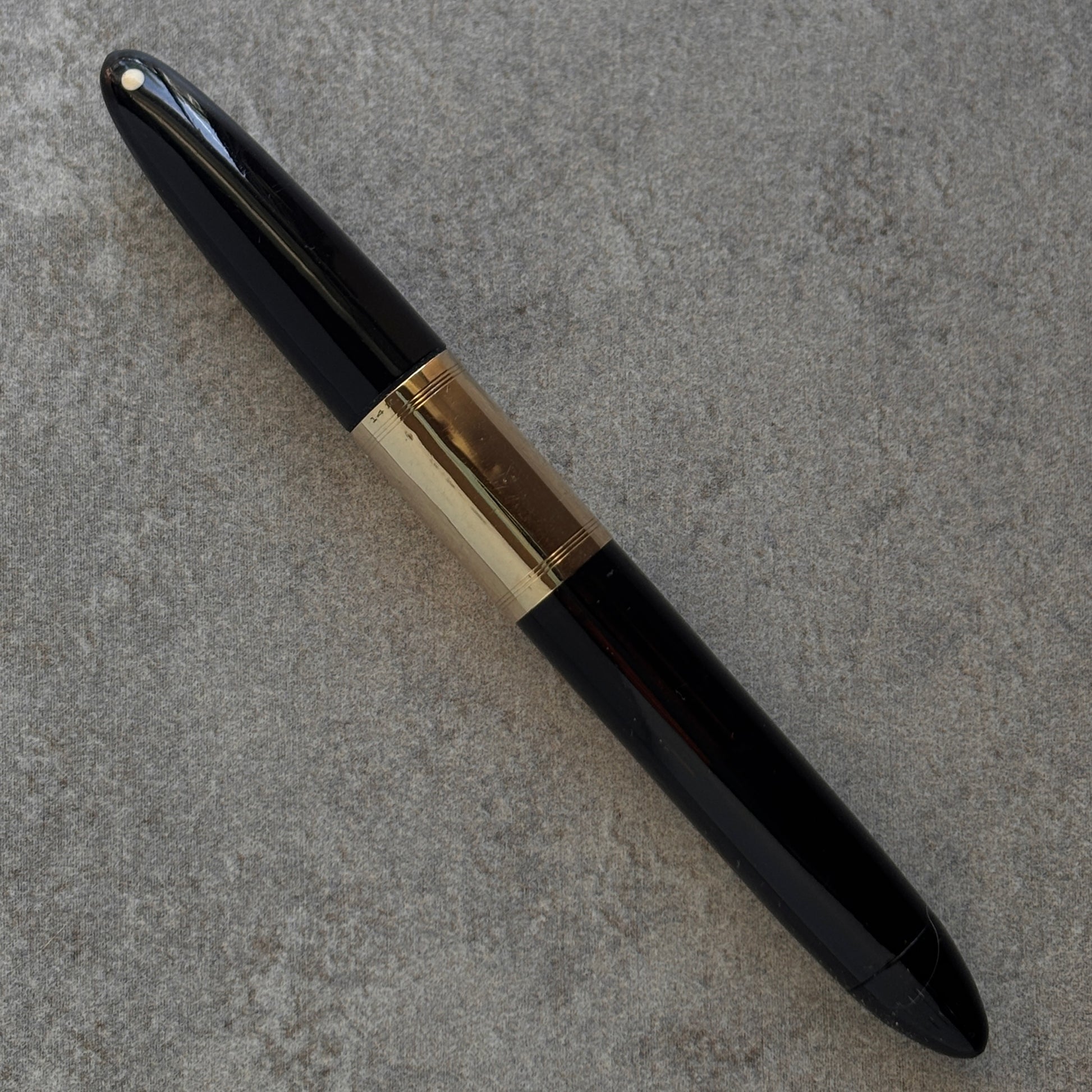 Black and gold pen on a gray textured surface