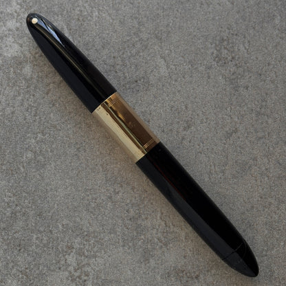 Black and gold pen on a gray textured surface