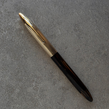 Pen with gold cap and black body on a gray textured surface